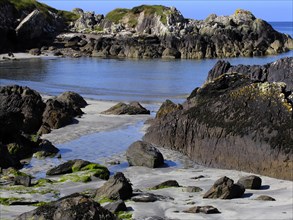 A tranquil coastal landscape with beach, rocks and seaweed under a blue sky Ireland