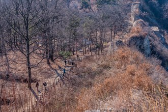 Unidentified tourists walking dirt hiking trail at Samnyeon Mountain Fortress in Boeun, South