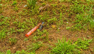Discarded tube on grassy terrain highlighting the problem of items left in nature, in South Korea