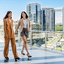 Two businesswomen are catching up while walking on their office terrace