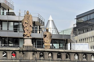 Two statues on a building look over the urban space, under a clear sky, Hamburg, Hanseatic City of