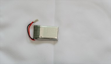 A single lithium polymer battery with red and black wires against a white backdrop, in South Korea