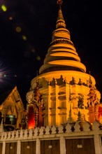 Illuminated temple with golden lights stands out against the dark night, in Chiang Mai, Thailand,