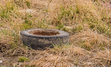 An old, rusty tire sitting in dry grass, in South Korea