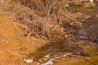A barren riverbank with signs of erosion and sparse vegetation during winter, in South Korea
