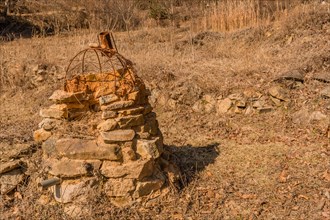 Stone structure with rusted wire frame and pipe sticking out of bottom in mountain park in Boeun,
