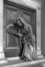 Sculpture of an old woman at a door with an hourglass, Monumental Cemetery, Cimitero monumentale di