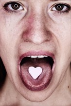 Woman with a heart of glucose on her outstretched tongue, studio shot, Germany, Europe