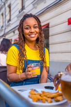 Vertical portrait of an african young woman sitting on a terrace of a restaurant