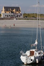 A sailing boat in the foreground with a sandy beach and a house in the background Ireland Tourism