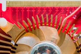 Closeup of copper heat sink and fan assembly mounted on red printed circuit board