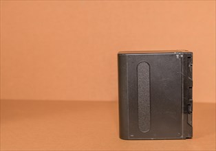 Closeup side view of used Lithium-ion battery on brown background