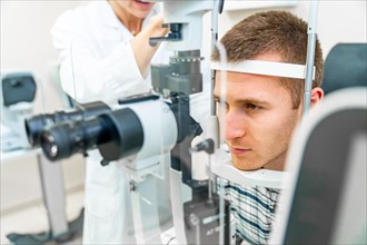 Man having his eyes checked at ophthalmologist by a female doctor