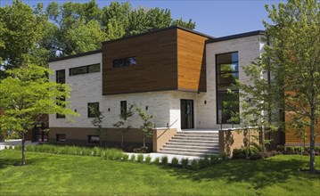 Beige stone with brown stained cedar wood modern cubist style residential home facade in spring,