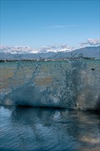 Water splashes in the foreground with the town of Sirmione and blue sky in the background,