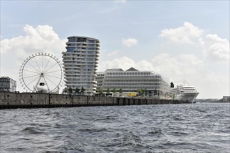 View of an urban skyline with a Ferris wheel and a cruise ship moored on the shore, Hamburg,