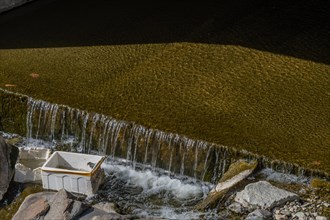 A white bucket caught in a cascade over algae-covered stones, in South Korea