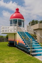 A vibrant red lighthouse with a blue staircase and green surroundings, in Ulsan, South Korea, Asia