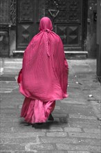 Woman with red robe in the streets of the historic centre, Genoa, Italy, Europe