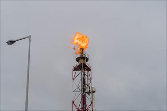 Flaring gas burns at the top of an industrial stack against a gloomy sky, in Ulsan, South Korea,