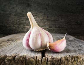 Food, spice, garlic, a whole garlic bulb next to a single clove on a rustic wooden surface, AI