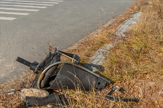 Broken office chair dumped on the side of a road amidst weeds and grass, in South Korea