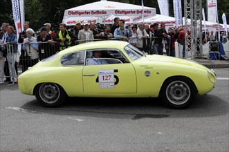 A yellow classic racing car with starting number 127 drives past spectators, SOLITUDE REVIVAL 2011,
