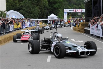 Various formula racing cars at the starting line of a motorsport event with spectators in the