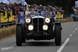 Historic racing car drives past the public at night with its headlights switched on, SOLITUDE
