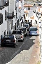 Solabrena, Narrow urban street with parked cars and traditional white houses, Costa del Sol,