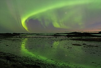 Northern Lights (Aurora Borealis) reflected in the calm waters of a shallow lake, Offersoey,
