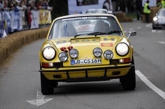 A classic yellow Porsche 911 on a rally track, flanked by spectators, SOLITUDE REVIVAL 2011,