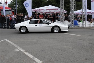 A white vintage car takes part in a motorsport event in front of an audience, SOLITUDE REVIVAL