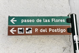 Two green signposts point the way to 'Paseo de las Flores' and 'P. del Postigo', Andalusia, Spain,