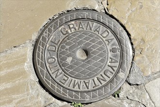 Granada, Round manhole cover with the inscription 'Granada' on a cobbled floor, Granada, Andalusia,