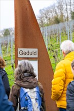 Visitors on a learning path in the vineyard, passing a sign 'patience', Jesus Grace Chruch,