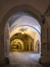 Inner courtyard in the Gothic part of the town hall at night, portal and passageway with lanterns,