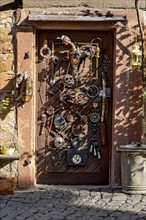 Entrance door whimsically decorated, old half-timbered house, masks, skulls, engine parts,