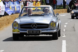 A silver Mercedes-Benz 300SL Roadster racing in front of a dense crowd of spectators, SOLITUDE
