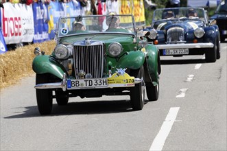 A green MG vintage car at a road race, surrounded by spectators, SOLITUDE REVIVAL 2011, Stuttgart,