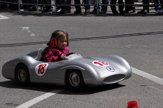A child in a silver soapbox experiences the feeling of racing in front of spectators, SOLITUDE