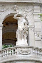 Palais Longchamp, Marseille, A marble statue of a boy holding a winged creature on a building,