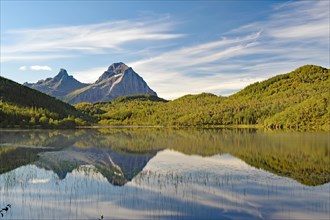 Striking mountains reflected in the calm waters of a small lake, fog, Askarget, Halsa,