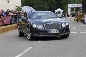 Black Bentley sports car drives along in front of spectators at a racing event, SOLITUDE REVIVAL