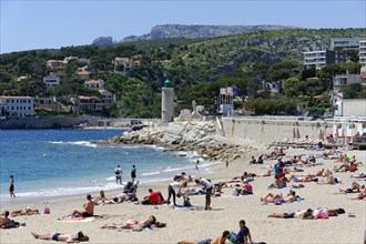 The bay of Port Miou in Cassis, people sunbathing on the beach with a view of the sea and nature,