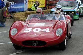A red vintage sports car with a driver in a helmet at a race, SOLITUDE REVIVAL 2011, Stuttgart,