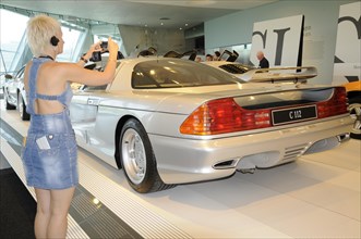 Museum, Mercedes-Benz Museum, Stuttgart, Woman takes a photo of the rear of a silver Mercedes-Benz