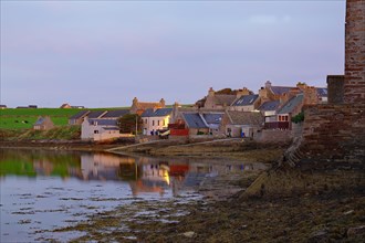 Stone houses by the sea in the last evening light, Orkney Islands, Scotland, UK