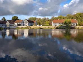 Half-timbered houses are reflected in the river Weisse Elster, Wuenschendorf (Elster), Thuringia,