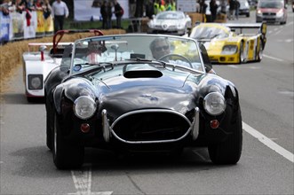 A black classic convertible racing car on a race track in front of spectators, SOLITUDE REVIVAL